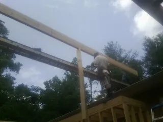 Carpenter setting a ridge beam over a new addition frame — Ice Dam Removal by Roofing Brothers in Hull