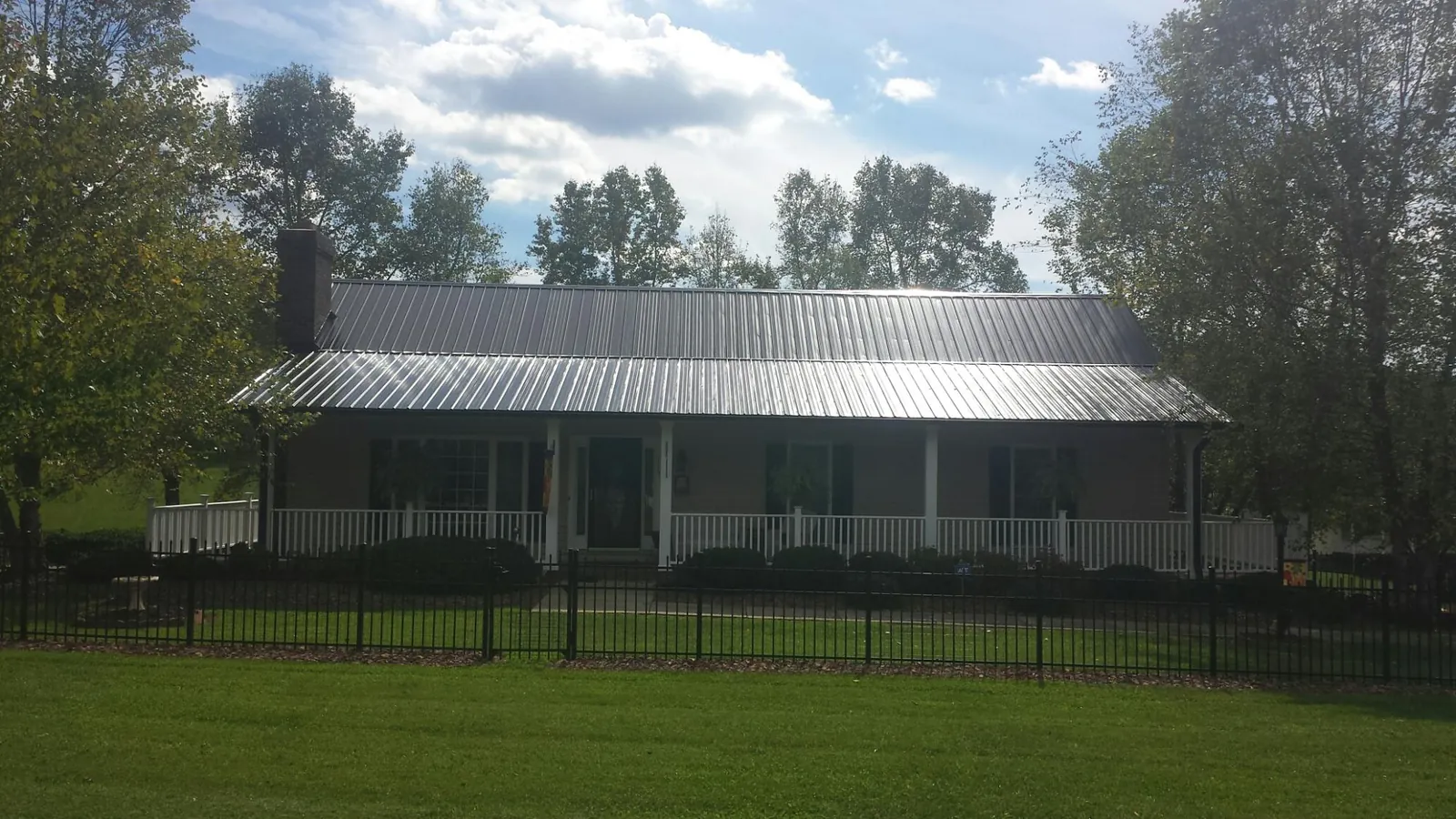 Gray metal roof on a brick ranch with a full width front porch — Gutter Guard Installation work by our crew in Hull