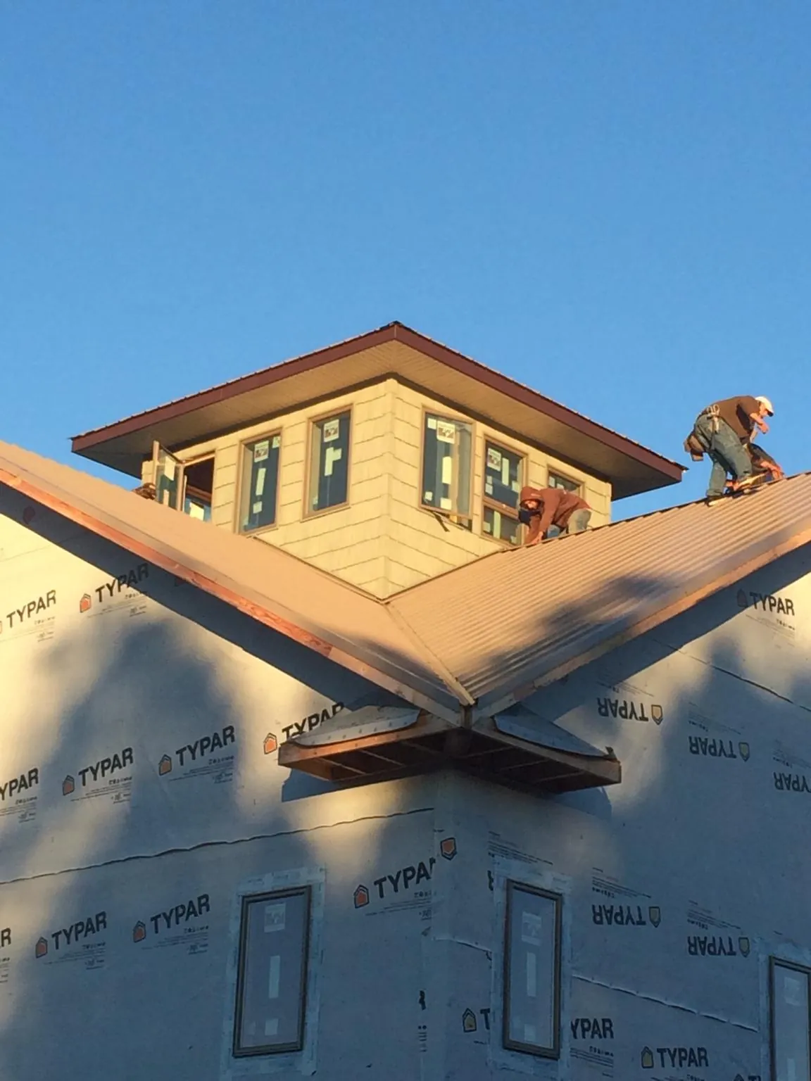 Roofers working around a rooftop cupola on a new metal roof at sunset — Roof Waterproofing in Hull by Roofing Brothers